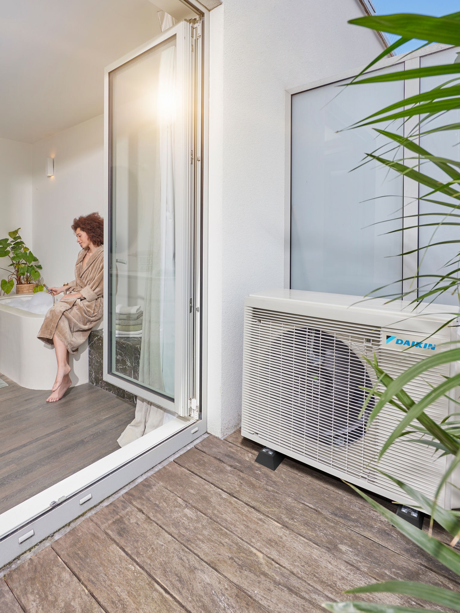 Luchtwarmtepomp geïnstalleerd naast het terras met open deuren naar een moderne badkamer