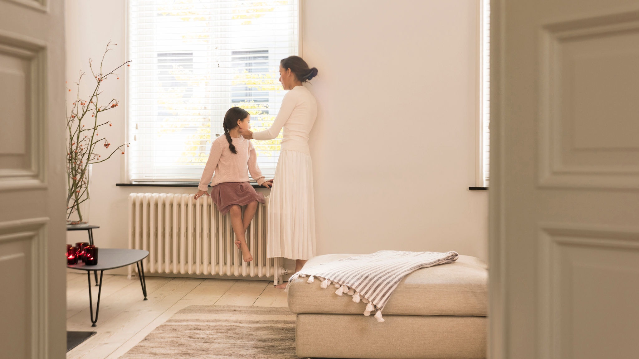 Mère et fille regardant par la fenêtre depuis leur salon parfaitement chauffé