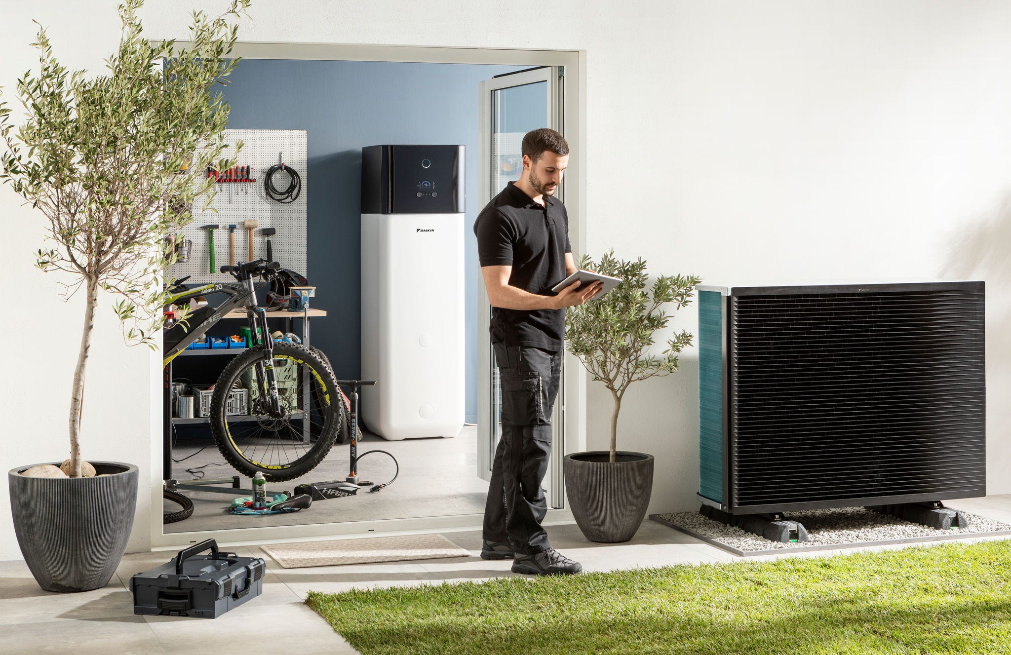 Installateur controleert buitenunit van luchtwarmtepomp en warmwatertank