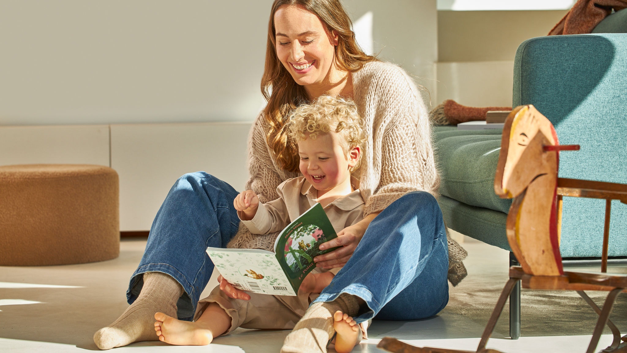 Une mère et son petit garçon assis, souriant et regardant un livre