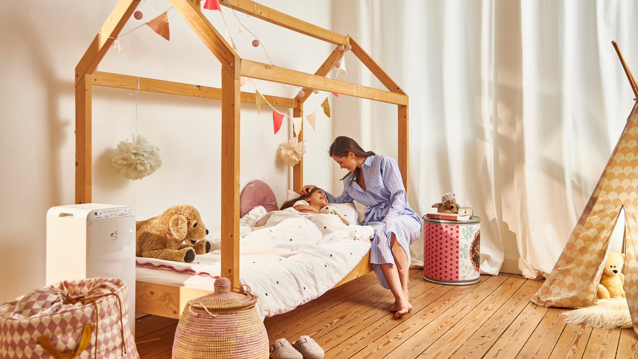 Une mère met son enfant au lit dans un logement sain grâce au purificateur d'air Daikin installé dans la chambre d’enfant.