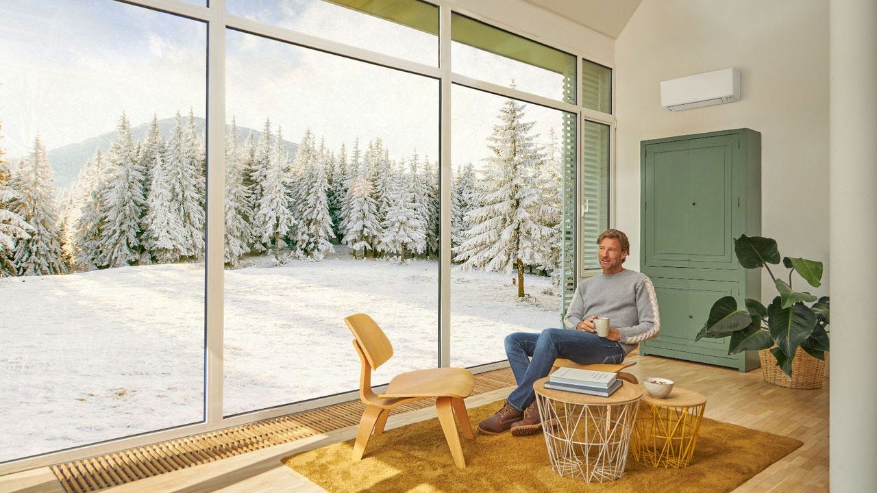 Homme assis sur un canapé, profitant du chauffage assuré par un climatiseur