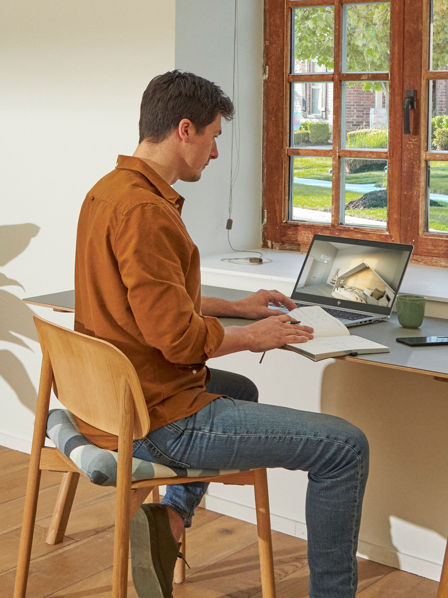 Man zit aan zijn bureau en bekijkt airconditioners in de Virtuele Showroom op zijn laptop