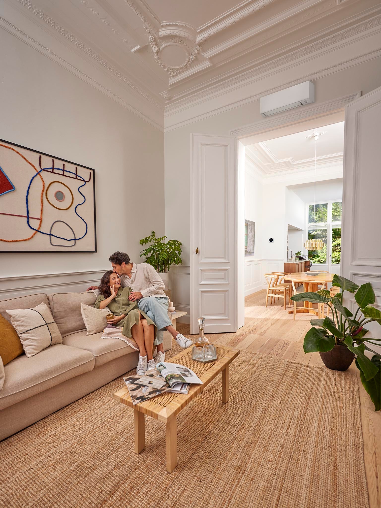 Een koppel dat zich binnen aan het ontspannen is, terwijl een airco met inverter voor comfort zorgt