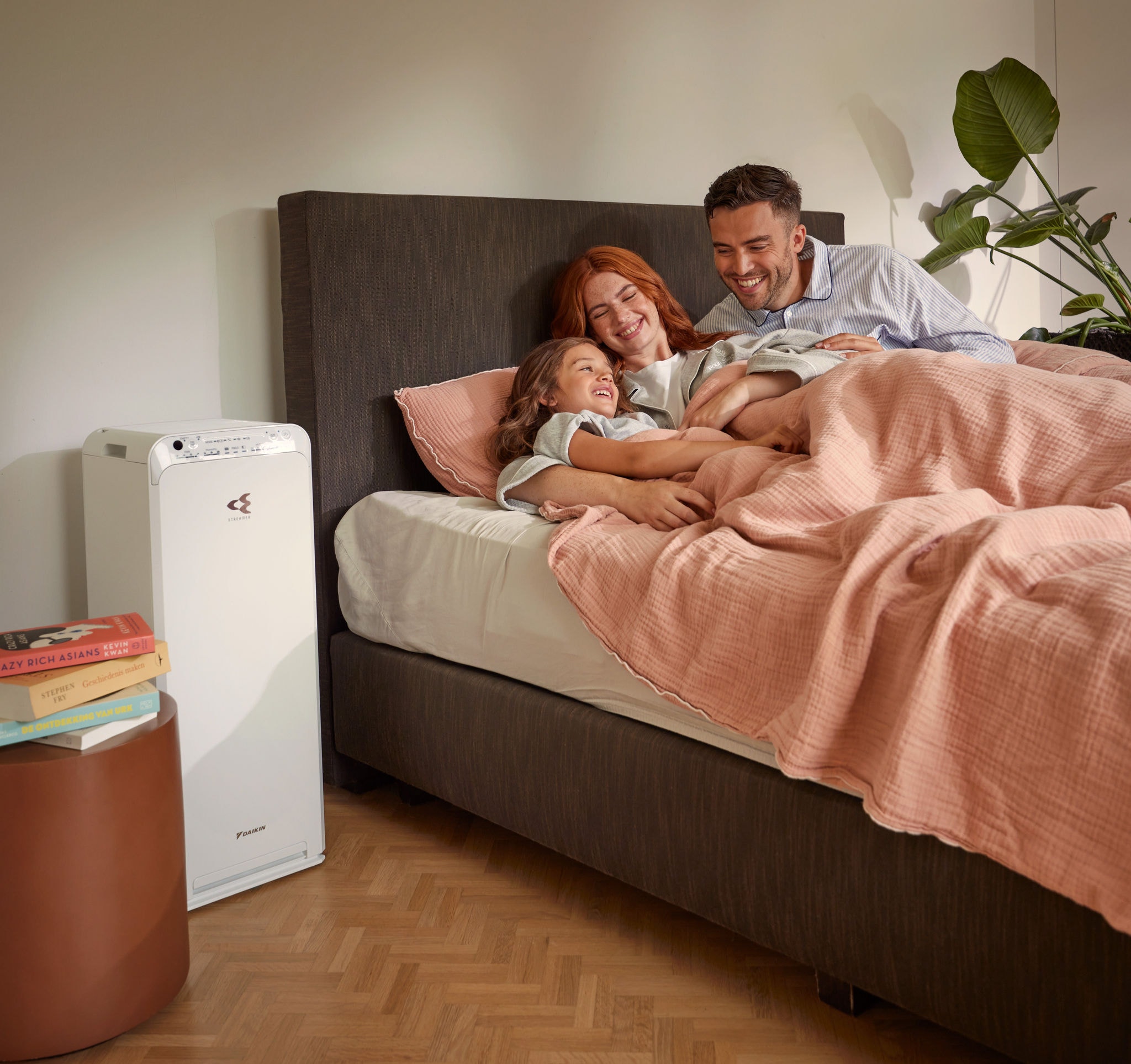 Un couple avec un enfant se détend dans sa chambre et profite de l'air purifié par un purificateur d'air.