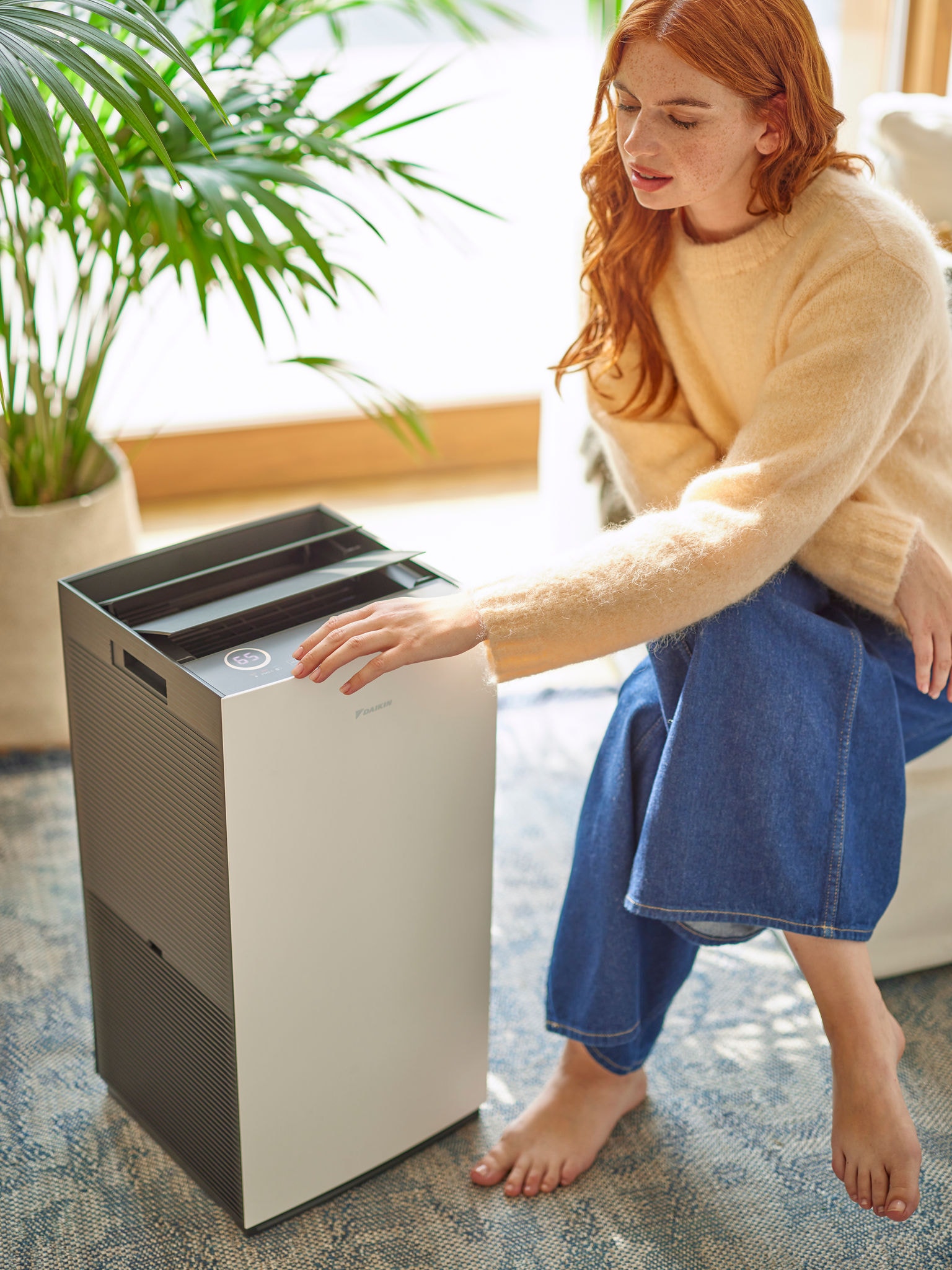 Vrouw in woonkamer die een Daikin-luchtreiniger aan het bedienen is