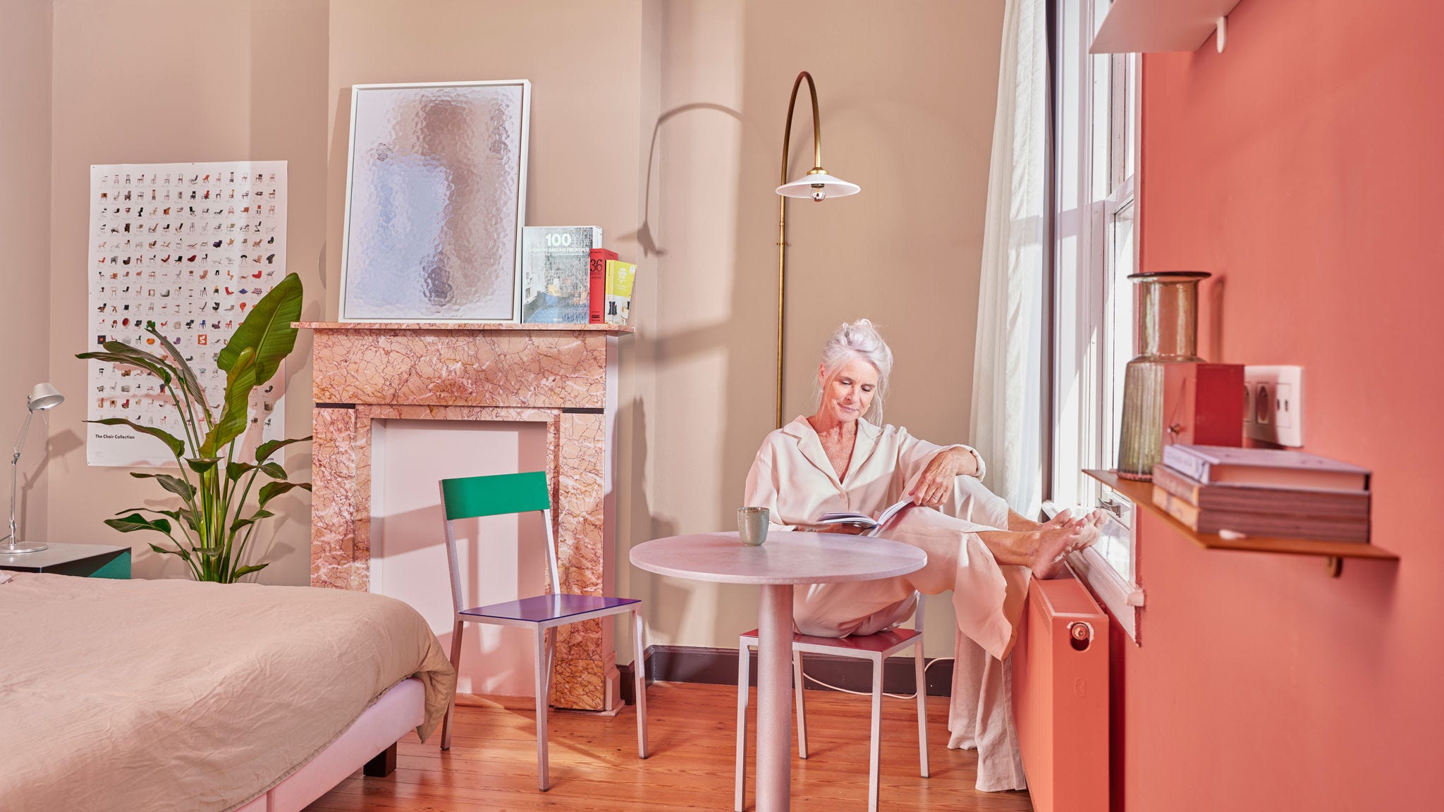 Oudere vrouw geniet van een radiator met lage temperatuur in een gezellige slaapkamer met warmtepomp