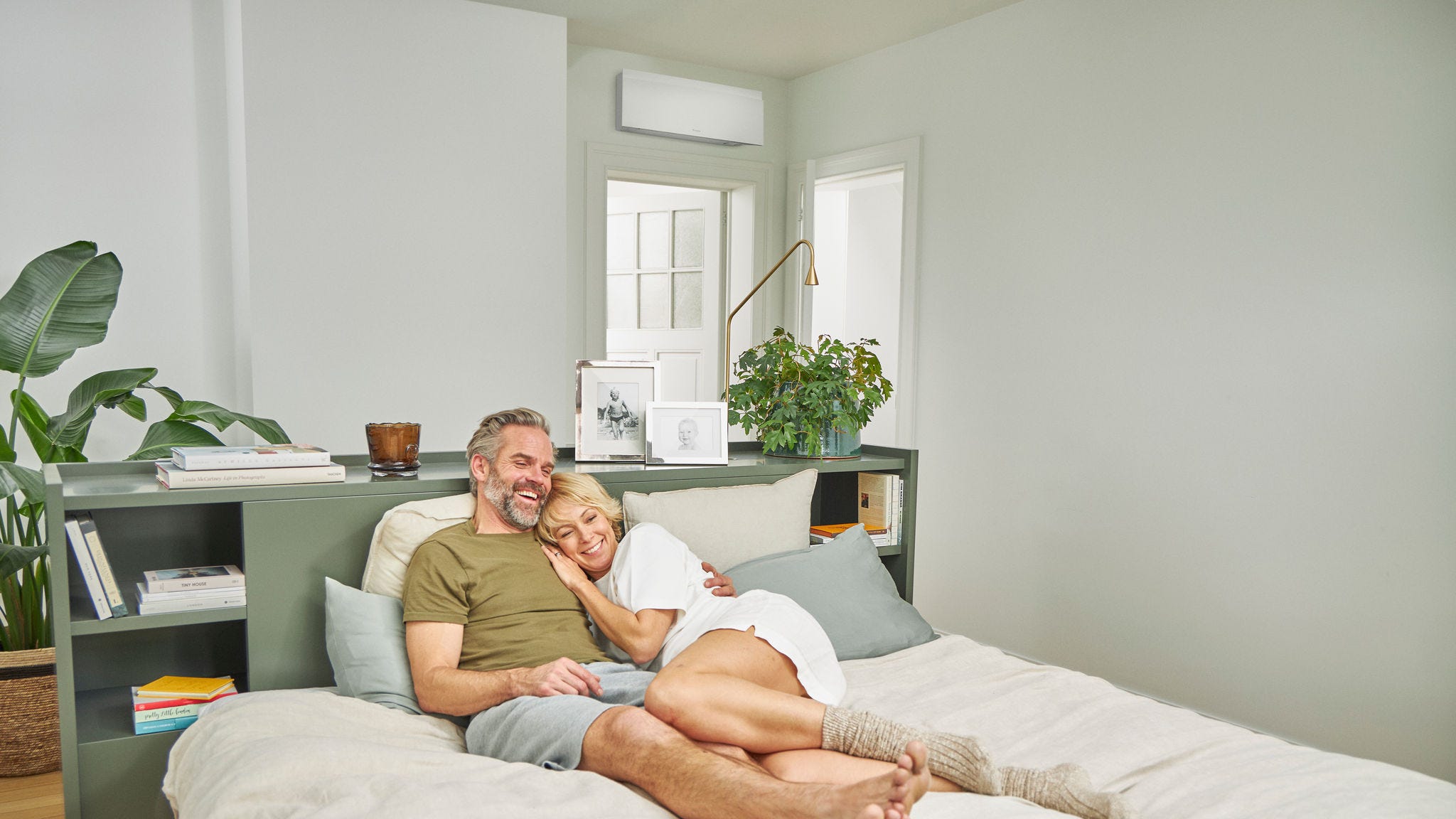 Een koppel ontspant zich op een bed in een koele slaapkamer met een stille airco