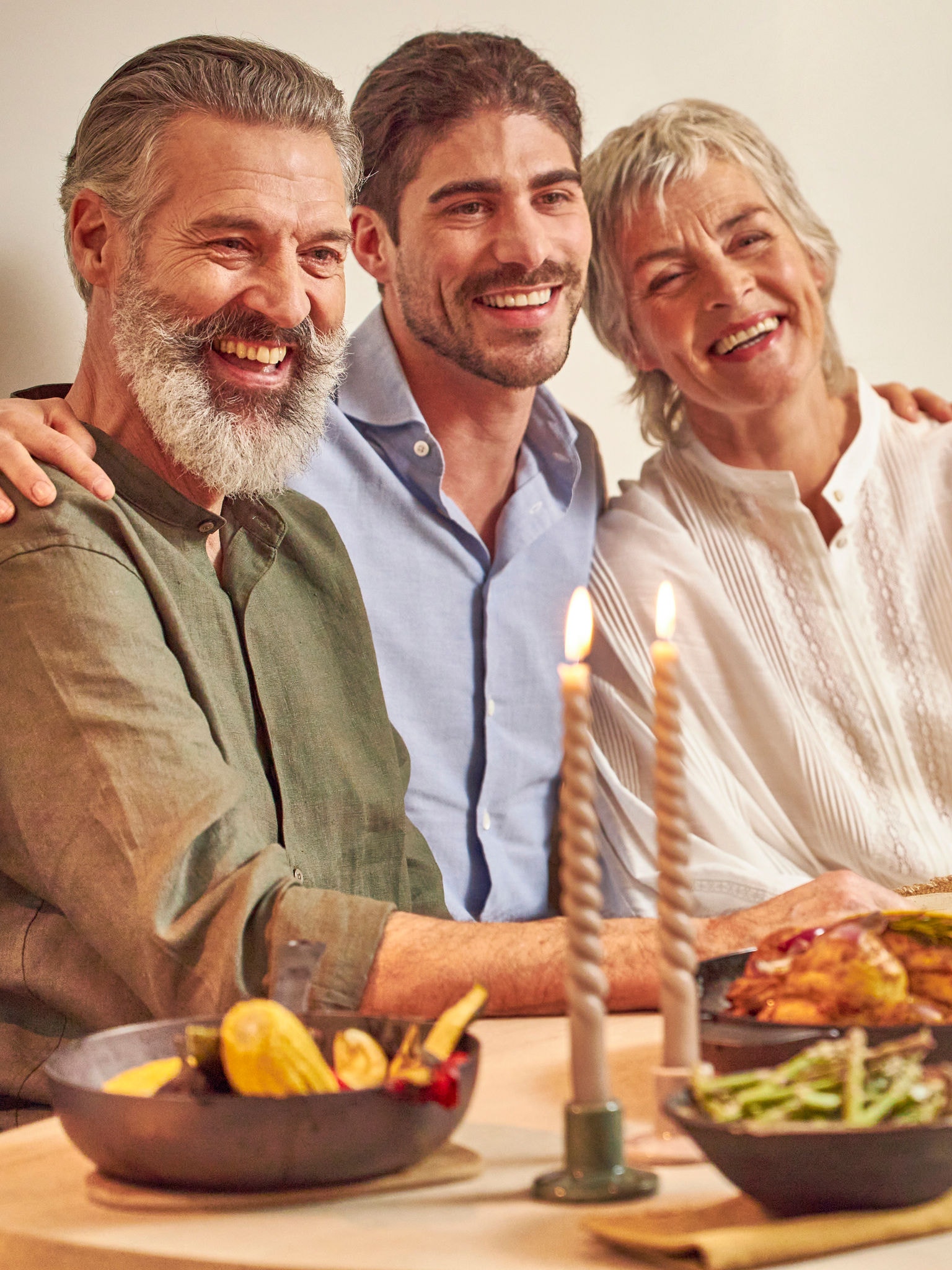 Fils adulte avec ses parents, joyeusement assis à la table du dîner