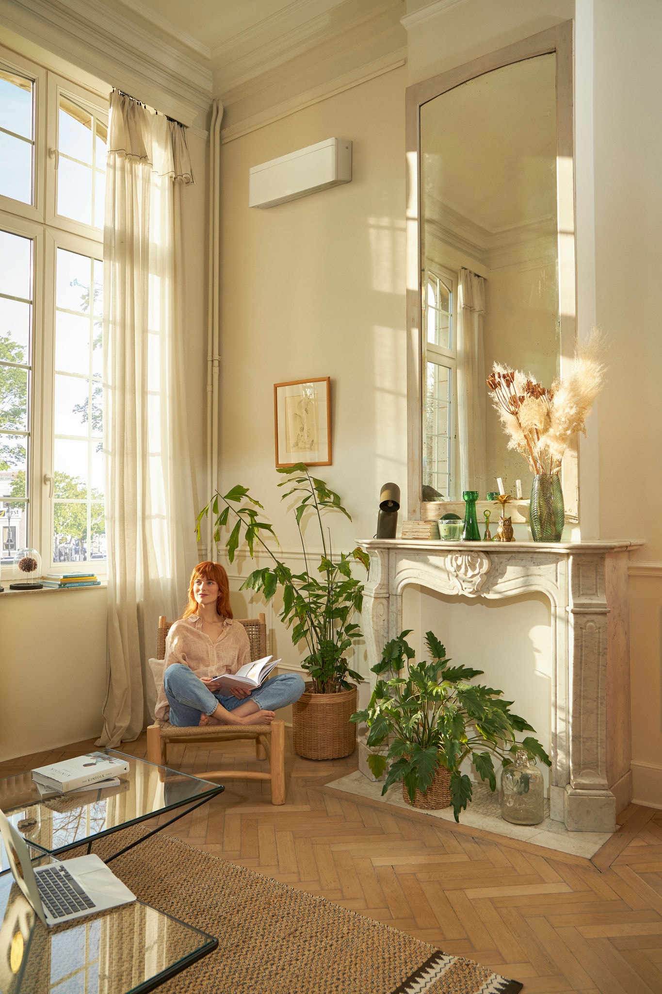 Vrouw die een tijdschrift leest in een kamer vol planten met een airco met inverter