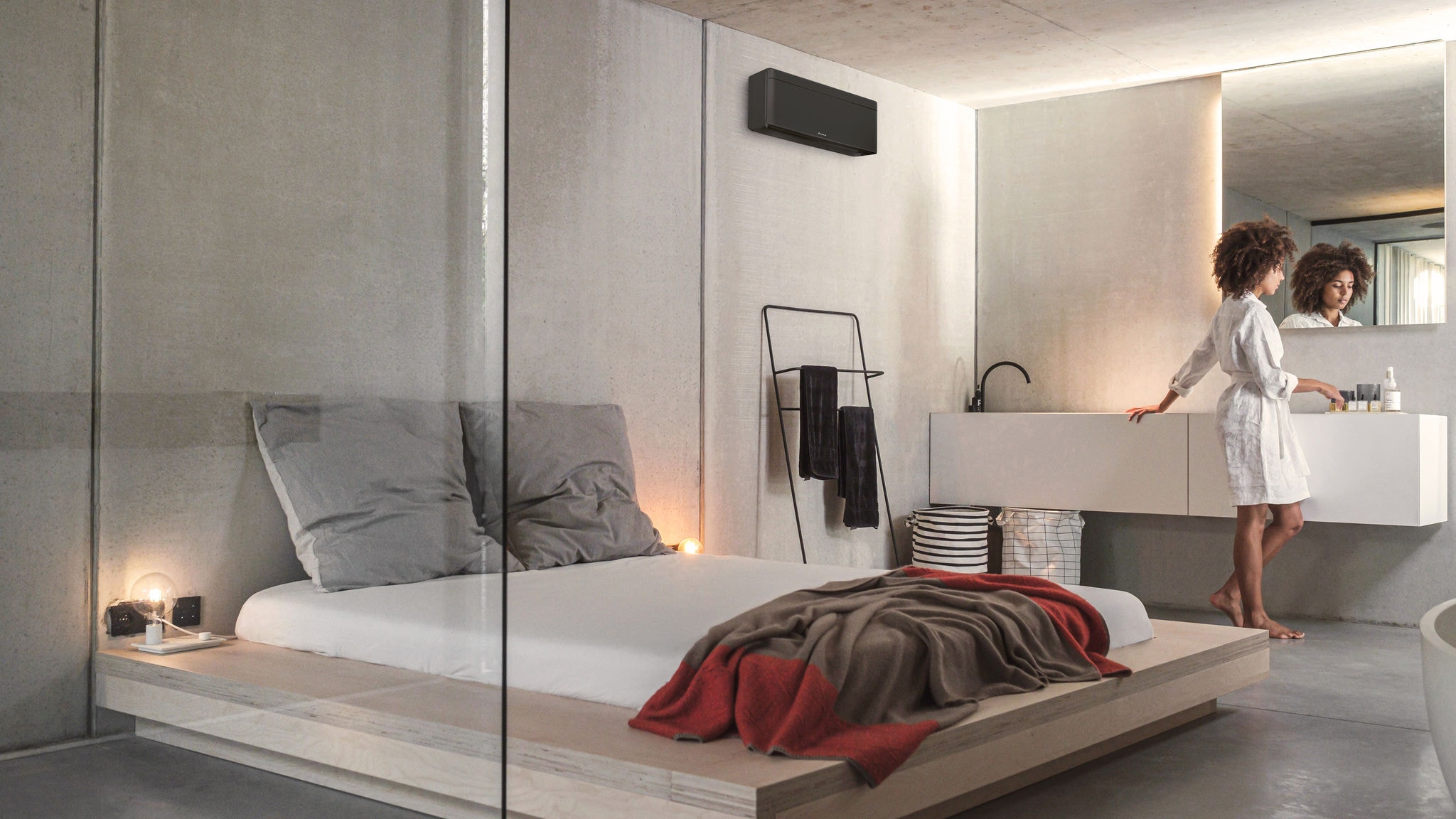 Een vrouw bereidt zich voor op de dag in haar slaapkamer met geïntegreerde badkamer die wordt verwarmd en waarin de lucht wordt geklimatiseerd door een Stylish-binnenunit