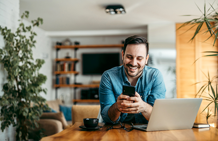 Home regardant son téléphone portable chez lui
